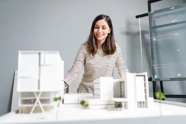 attractive-smiling-engineer-looking-architectural-model-workplace-scaled